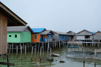 Houses in lake by building against clear sky