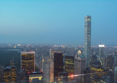 View of skyscrapers lit up against blue sky