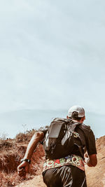 Rear view of man riding motorcycle sitting on land against sky