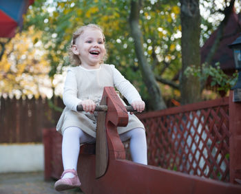 Smiling girl sitting on rocking horse outdoors