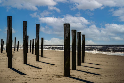 Wooden posts on beach against sky