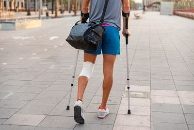 Unrecognizable young man with crutches walking in the city