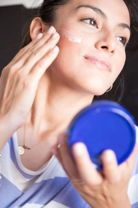 Close-up of young woman applying beauty product