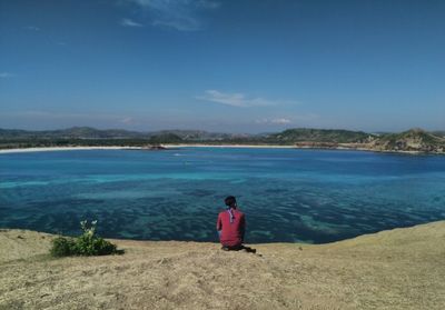 Rear view of woman standing at beach against sky