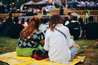 Rear view of people sitting on field