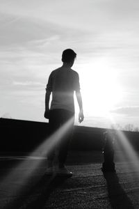 Rear view of silhouette man walking on road