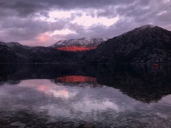 Scenic view of lake by mountains against sky during sunset