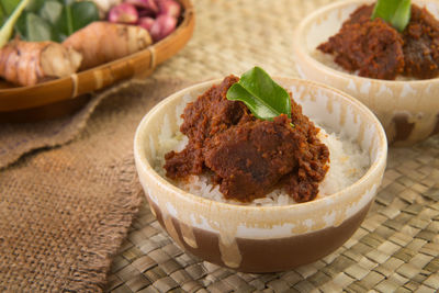 Bowl of steamed rice topped with spicy chutney on wicker mat