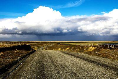 Road amidst field against sky