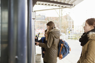 School students buying tickets from automated machine at train station