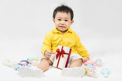 Portrait of cute girl playing with toy against white background