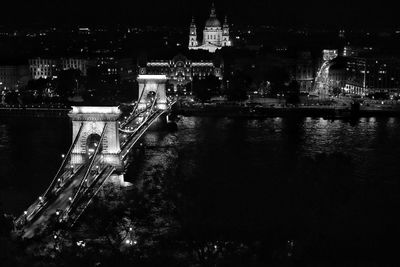 Illuminated bridge over river in city at night