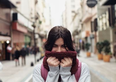 Portrait of young woman holding scarf against face