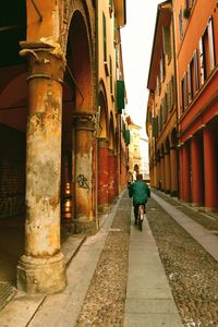 Rear view of woman walking on street amidst buildings