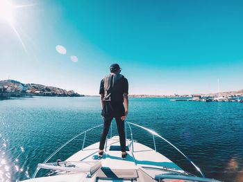 People standing on boat sailing in sea against clear blue sky