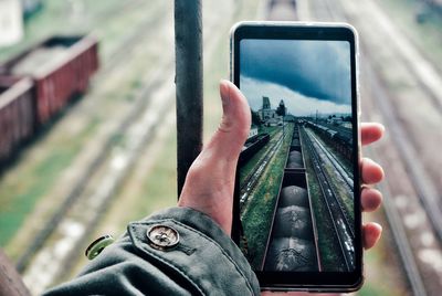 Midsection of person photographing with mobile phone