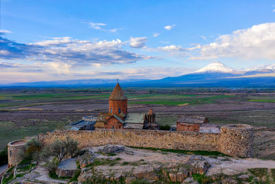 Old building on mountain against cloudy sky