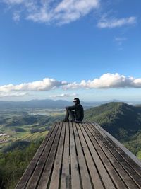 Man sitting on observation point against blue sky