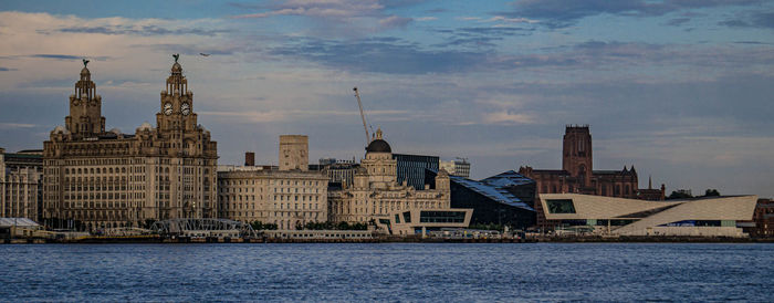 View of buildings at waterfront against cloudy sky