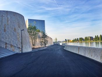 Road by buildings in city against sky