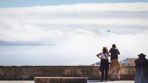 People on mountain against cloudy sky