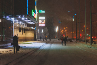 People on snow covered city at night