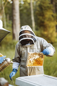 Beekeeper holding honeycomb on field