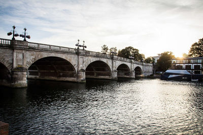 Arch bridge over river against sky in city