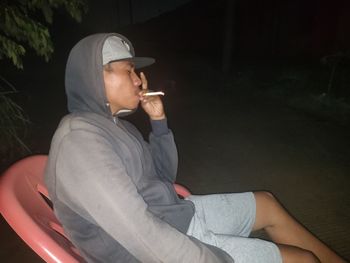 Side view of young man smoking cigarette