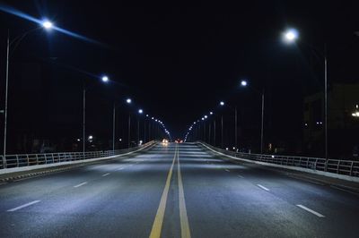 Empty road in city against sky at night