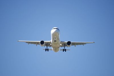 Low angle view of airplane flying against clear blue sky