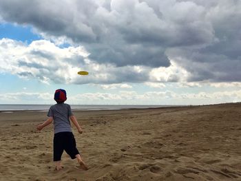 Full length rear view of girl playing on beach