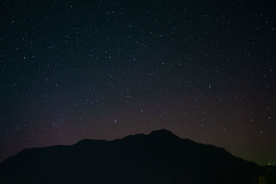 Low angle view of silhouette mountain against sky at night