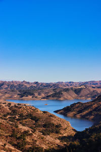 Scenic view of lake and mountains against clear blue sky