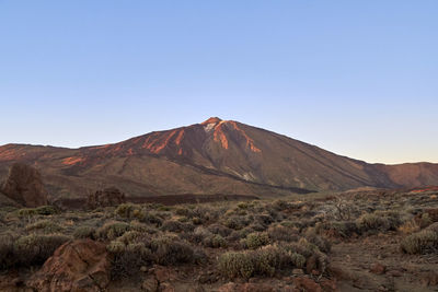 Scenic view of arid landscape against clear blue sky