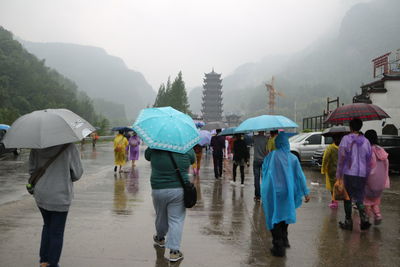 People holding umbrella while walking on road in rainy season