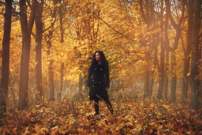 Full length of woman standing in autumn forest