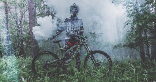 Man with mountain bike holding smoke bomb in forest