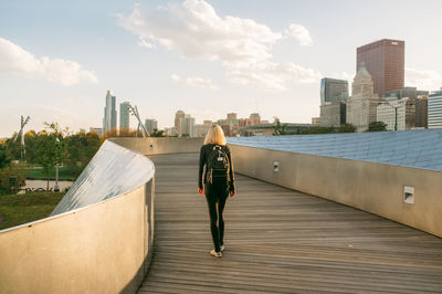 Rear view of woman on bp bridge by modern buildings in city