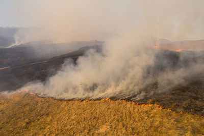 Aerial view of spring dry grass burning field. fire and smoke in the meadow, nature pollution