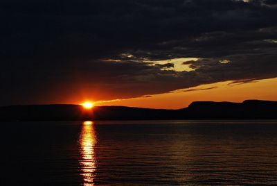 Scenic view of sea against dramatic sky during sunset