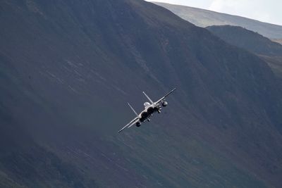 Airplane flying over mountains against sky