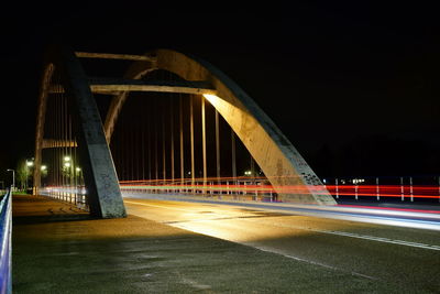 Light trails on bridge against sky at night