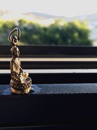 Close-up of buddha statue on wet window sill