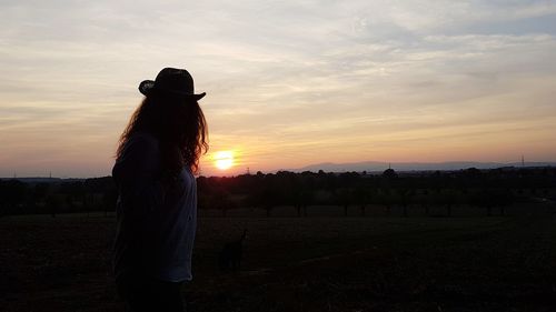 Silhouette person standing on field against sky during sunset