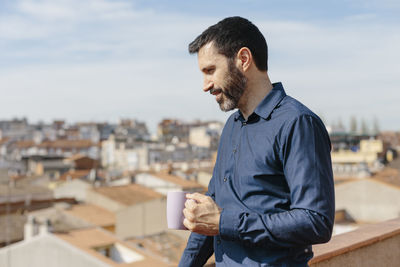 Young man drinking coffee with cityscape in background