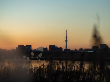 Silhouette of city at riverbank during sunset