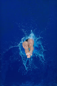 High angle view of mid adult woman wearing bikini while jumping in swimming pool