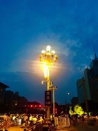 People in illuminated city against sky at night