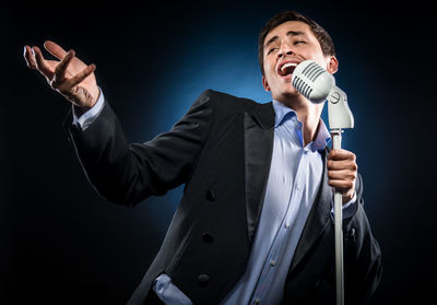Opera singer singing while standing against black background